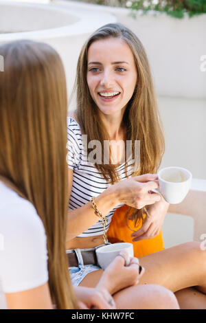 Zwei junge weibliche Freunde im Straßencafé chatten Stockfoto