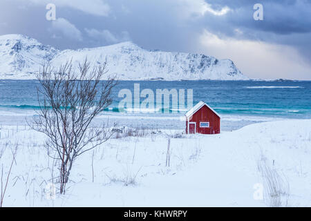 Ein typisches Haus der Fischer namens Rorbu auf den verschneiten Strand Frames der eisigen Meer bei Ramberg Lofoten Inseln, Norwegen Europa Stockfoto