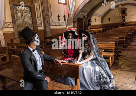 Mexikanische Teenager in La Calavera Catrina und Dapper Skelett Kostüme sitzen im Templo del Sagrario während des Tages der Toten oder Día de Muertos Festival 31. Oktober 2017 in Patzcuaro, Michoacan, Mexiko. Das Fest wird seit dem aztekischen Reich gefeiert feiert Vorfahren und verstorbene Lieben. Stockfoto