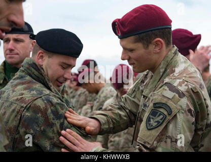 Ein Fallschirmjäger auf die 173Rd Airborne Brigade zugeordnet trades Schulter Patches mit einem serbischen Streitkräfte Fallschirmjäger auf Lisicji Jarak Flughafen, Serbien, Nov. 17, 2017. Usa und Serbischen Fallschirmjäger durchgeführt Airborne insertion Übungen zusammen, die während der Übung Doppeladler, voneinander zu lernen und Beziehungen aufzubauen, dass die regionale Sicherheit zu fördern. (U.S. Air Force Foto von älteren Flieger Elizabeth Baker) Stockfoto