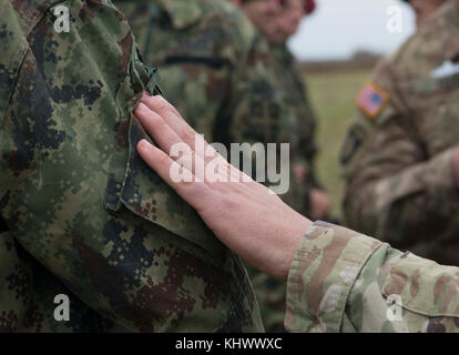 Ein Fallschirmjäger auf die 173Rd Airborne Brigade zugeordnet trades Schulter Patches mit einem serbischen Streitkräfte Fallschirmjäger auf Lisicji Jarak Flughafen, Serbien, Nov. 17, 2017. Usa und Serbischen Fallschirmjäger durchgeführt Airborne insertion Übungen zusammen, die während der Übung Doppeladler, voneinander zu lernen und bauen Beziehungen auf die regionale Sicherheit zu fördern. (U.S. Air Force Foto von älteren Flieger Elizabeth Baker) Stockfoto