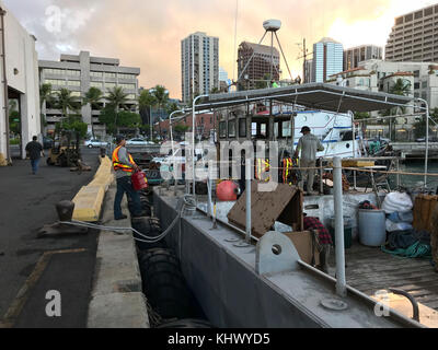 Mitglieder der Pacific Paradise response team bereiten die Dive station an Bord der JW Barnes, ein landungsboot durch als Arbeit barge verwendet wird, während an der Pier in Honolulu, Nov. 16, 2017. Die ersthelfer sind die Vorbereitung der Pacific Paradise refloated und beseitigt werden. (U.S. Coast Guard Foto/Freigegeben) Stockfoto