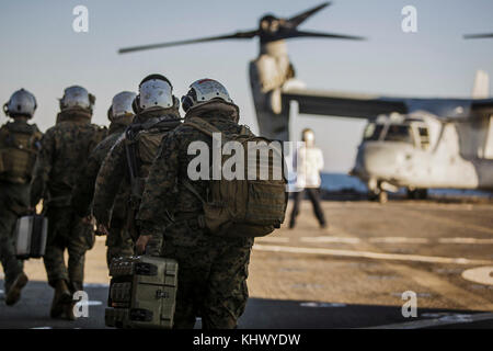 Us-Marines mit Fox Company, Bataillon Landung Team, 2.BATAILLON, 6 Marine Regiment, 26 Marine Expeditionary Unit (MEU), Spaziergang in Vorbereitung einer MV-22 B Osprey Flugzeuge mit Marine Medium Tiltrotor Squadron 162 (verstärkt), 26 MEU, fliegen zu den amphibischen Angriff Schiff USS Iwo Jima (LHD7) zur Unterstützung der kombinierten Composite Trainingsgerät Übung an Bord der Station Landung Schiff USS Oak Hill (LSD) im Atlantischen Ozean, Nov. 16, 2017. COMPTUEX können alle Elemente der Marine Air Ground Task Force beitreten in realistischen Szenarien, also der MEU als Ganzes trainieren und kann seine Predeplo treffen Stockfoto