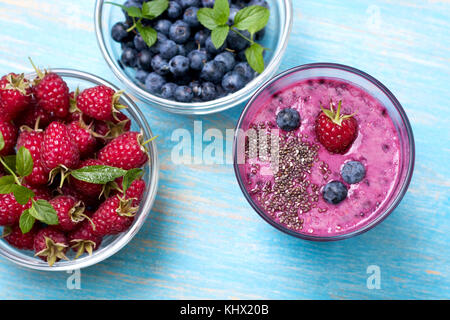 Smoothie mit Blaubeeren und Himbeeren, Chia Samen in ein Glas, frische Heidelbeeren und Himbeeren auf alten hölzernen Hintergrund. Ansicht von oben Stockfoto