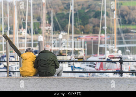 Ein reifes Paar Leute zusammen sitzen auf Schritte mit Blick auf eine Marina in Falmouth Cornwall UK. Stockfoto