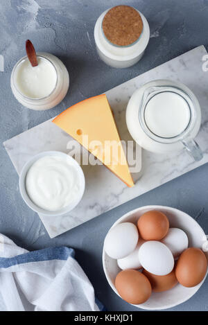 Auswahl der Milchprodukte auf Marmor Hintergrund. Eier, Käse, Milch, Joghurt, Sauerrahm und Sahne. Ansicht von oben Stockfoto