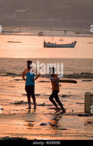 Junge Männer Kricket spielen bei Sonnenuntergang am Strand, versova Mumbai Stockfoto
