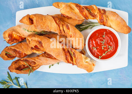 Leckere Käsestange mit Speck, Kräuter und Tomatensauce. top Aussicht, blauen Hintergrund. Fleisch Käse Snack für Bier, party Konzept, Tag Thanksgiving. Stockfoto