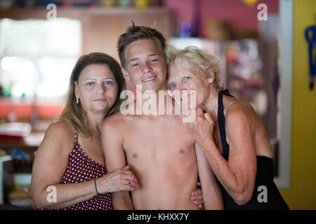 Family Portrait, zwei ältere Frauen umarmen Teenager Stockfoto