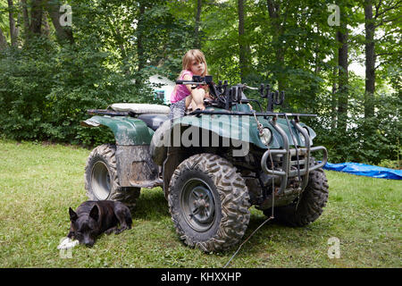 Portrait von Mädchen sitzen auf Quad, Hund neben entspannenden Stockfoto