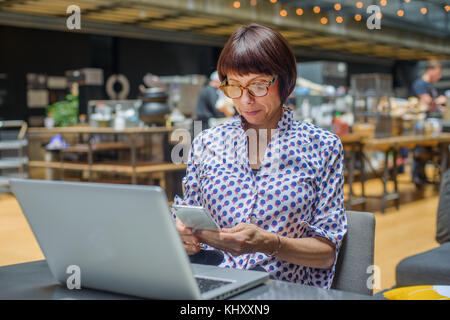 Frau im Büro mit smartphone Stockfoto