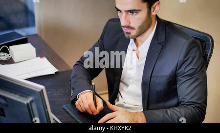 Junge eleganten Mann zeichnen mit Grafiktablett und Schreibtisch posieren. Stockfoto