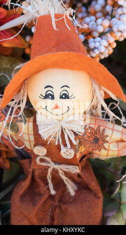Vertikaler Vogelscheuche Puppe, mit freundlichem Ausdruck, aus Stoff, mit Sackleinen, Overalls, übergroße orange Hut, und bemaltem Gesicht. Stockfoto