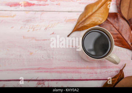 Blick von oben auf eine Tasse Kaffee mit Herbstlaub auf rustikalen Holzmöbeln Hintergrund mit Kopie Raum Stockfoto