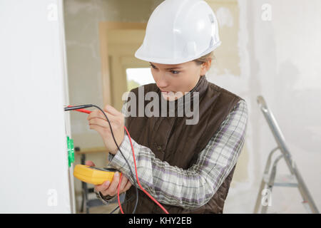 Junge weibliche Elektriker installieren elektrische Steckdose an der Wand Stockfoto