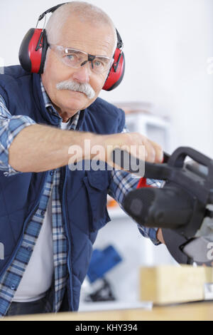 Ältere Menschen Tragen von Gehörschutz, während mit Kreissäge Stockfoto