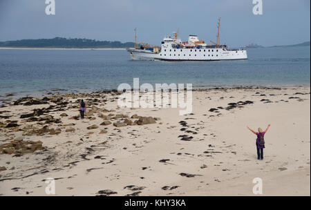 Frau winken auf bar Point Beach als rmv scillonian iii Fähre geht En-route von Penzance zu St Mary's, Isles of Scilly, Cornwall, UK. Stockfoto