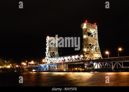 Die Portage Lake Lift Bridge, eine wichtige Verkehrsverbindung in Michigan, wird bei Nacht beleuchtet und zeigt ihre Zugbrücke für den Seeverkehr. Stockfoto
