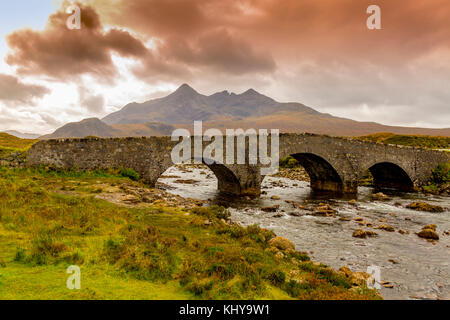 Dunkle Wolken hängen über den schroffen Gipfeln der Black Cuillin Hills und die River Sligachan auf der Insel Skye, Schottland, Großbritannien Stockfoto