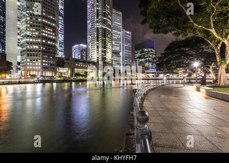 Die Lichter der Wolkenkratzer des Financial District spiegeln sich im Wasser des Singapore River entlang der Jubiläums Spaziergang bei Nacht in Singapur, Süd Stockfoto