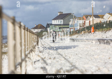 Tywyn, Großbritannien. 23 Nov, 2017. de Wetter. ein Mann Zyklen durch Sea Foam, deckt das Meer in tywyn, in der Nähe von Aberdovey, den Eindruck zu erwecken, dass es schneit wurde. Quelle: Jon Freeman/alamy leben Nachrichten Stockfoto