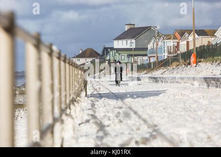 Tywyn, Großbritannien. 23 Nov, 2017. de Wetter. ein Mann Zyklen durch Sea Foam, deckt das Meer in tywyn, in der Nähe von Aberdovey, den Eindruck zu erwecken, dass es schneit wurde. Quelle: Jon Freeman/alamy leben Nachrichten Stockfoto