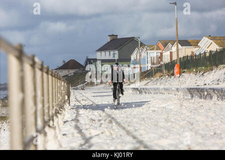 Tywyn, Großbritannien. 23 Nov, 2017. de Wetter. ein Mann Zyklen durch Sea Foam, deckt das Meer in tywyn, in der Nähe von Aberdovey, den Eindruck zu erwecken, dass es schneit wurde. Quelle: Jon Freeman/alamy leben Nachrichten Stockfoto