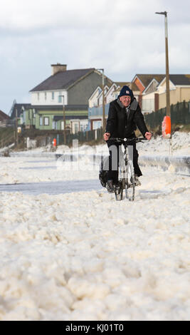 Tywyn, Großbritannien. 23 Nov, 2017. de Wetter. ein Mann Zyklen durch Sea Foam, deckt das Meer in tywyn, in der Nähe von Aberdovey, den Eindruck zu erwecken, dass es schneit wurde. Quelle: Jon Freeman/alamy leben Nachrichten Stockfoto