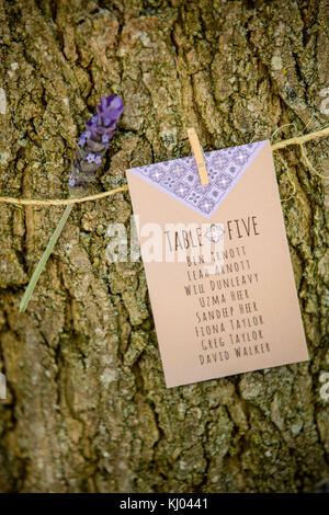 Hochzeit Tabelle Gästeliste an Baumstamm mit Lavendel Stammzellen gebunden, in der Nähe Stockfoto