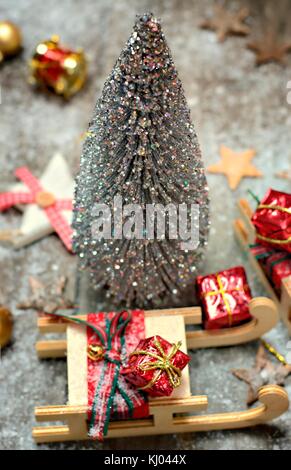 Weihnachtsdekoration, Feiertage und Einrichtung Konzept - Silber Weihnachtsbaum, Schlitten und Geschenken auf Schnee Hintergrund. Stockfoto