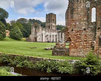 England, NorthYorkshire; die Ruinen des 12. Jahrhunderts Zisterzienserabtei als Fountains Abbey, eines der schönsten Beispiele der klösterlichen Architektur in der Welt bekannt. Der Turm von Abt Huby, (1495-1526), dominiert das Tal noch Landschaft. Zusammen mit seinen umliegenden 800 Morgen des 18.Jahrhunderts angelegten Parklandschaft, Fountains Abbey wurde von der UNESCO zum Weltkulturerbe ernannt. North Yorkshire, England, UK. Ca. 1995. | Lage: in der Nähe von Bedale, Yorkshire, England, UK. Stockfoto