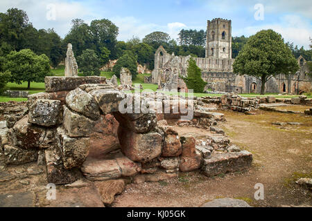 England, NorthYorkshire; die Ruinen des 12. Jahrhunderts Zisterzienserabtei als Fountains Abbey, eines der schönsten Beispiele der klösterlichen Architektur in der Welt bekannt. Der Turm von Abt Huby, (1495-1526), dominiert das Tal noch Landschaft. Zusammen mit seinen umliegenden 800 Morgen des 18.Jahrhunderts angelegten Parklandschaft, Fountains Abbey wurde von der UNESCO zum Weltkulturerbe ernannt. North Yorkshire, England, UK. Ca. 1995. | Lage: in der Nähe von Bedale, Yorkshire, England, UK. Stockfoto