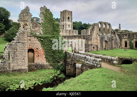 England, NorthYorkshire; die Ruinen des 12. Jahrhunderts Zisterzienserabtei als Fountains Abbey, eines der schönsten Beispiele der klösterlichen Architektur in der Welt bekannt. Der Turm von Abt Huby, (1495-1526), dominiert das Tal noch Landschaft. Zusammen mit seinen umliegenden 800 Morgen des 18.Jahrhunderts angelegten Parklandschaft, Fountains Abbey wurde von der UNESCO zum Weltkulturerbe ernannt. North Yorkshire, England, UK. Ca. 1995. | Lage: in der Nähe von Bedale, Yorkshire, England, UK. Stockfoto