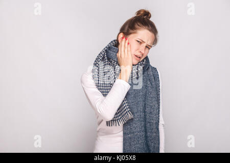 Kranke Frau die Hand Ihr cheeh, habe Zahnschmerzen. studio Shot, graue Wand Stockfoto