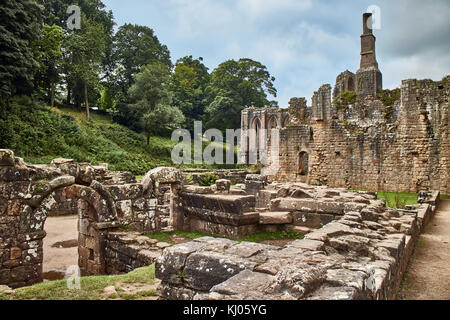 England, NorthYorkshire; die Ruinen des 12. Jahrhunderts Zisterzienserabtei als Fountains Abbey, eines der schönsten Beispiele der klösterlichen Architektur in der Welt bekannt. Der Turm von Abt Huby, (1495-1526), dominiert das Tal noch Landschaft. Zusammen mit seinen umliegenden 800 Morgen des 18.Jahrhunderts angelegten Parklandschaft, Fountains Abbey wurde von der UNESCO zum Weltkulturerbe ernannt. North Yorkshire, England, UK. Ca. 1995. | Lage: in der Nähe von Bedale, Yorkshire, England, UK. Stockfoto