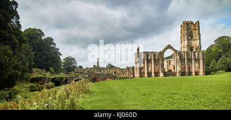 England, NorthYorkshire; die Ruinen des 12. Jahrhunderts Zisterzienserabtei als Fountains Abbey, eines der schönsten Beispiele der klösterlichen Architektur in der Welt bekannt. Der Turm von Abt Huby, (1495-1526), dominiert das Tal noch Landschaft. Zusammen mit seinen umliegenden 800 Morgen des 18.Jahrhunderts angelegten Parklandschaft, Fountains Abbey wurde von der UNESCO zum Weltkulturerbe ernannt. North Yorkshire, England, UK. Ca. 1995. | Lage: in der Nähe von Bedale, Yorkshire, England, UK. Stockfoto