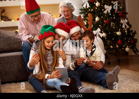 Familie zusammen an Heiligabend auf der Suche Fotos auf Tablet-PC zu Hause Stockfoto