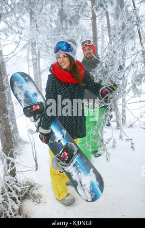 Junge Freunde Snowboarder gehen durch im Winter Wald Stockfoto