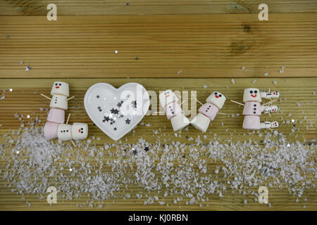 Winter fotografie Bild mit dem Wort Liebe in Marshmallows so glücklich Schneemann mit Iced auf Lächeln geformten geschrieben und bestreut mit Schnee Stockfoto