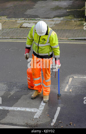 Männliche Arbeiter tragen Gut sichtbare Kleidung verbrennen alten Fahrbahnmarkierungen mit einer Flamme gun England Großbritannien Stockfoto