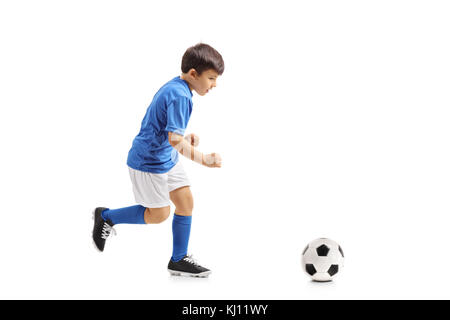 Volle Länge Profil Schuß eines kleinen Fußballer zu einem Fußball auf weißem Hintergrund läuft Stockfoto