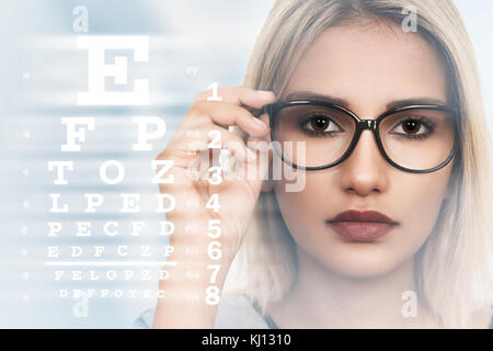 Junge Frau mit Brille auf Sehvermögen Test Chart Hintergrund Stockfoto