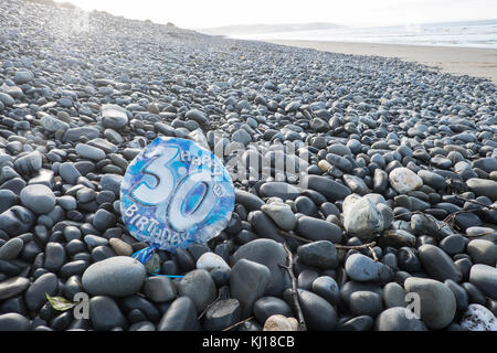 30., Geburtstag, Ballon, deflationiert, verschmutzen, Strand, gefunden, auf, Kiesel, ynyslas Strand, in der Nähe von Borth, Norden, der, Aberystwyth, Ceredigion, Mitte, West, Wales, Großbritannien, Großbritannien, Europa, Stockfoto