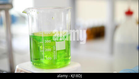 Mechanisches Rühren, Flüssigkeit der grünen Farbe gemischt in einer Runde Flasche. Stockfoto