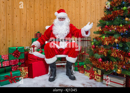 Santa Claus, ein Geschenk aus seinem Sack vorhanden gewickelt, wie er begrüßt Sie in seiner Grotte. Stockfoto