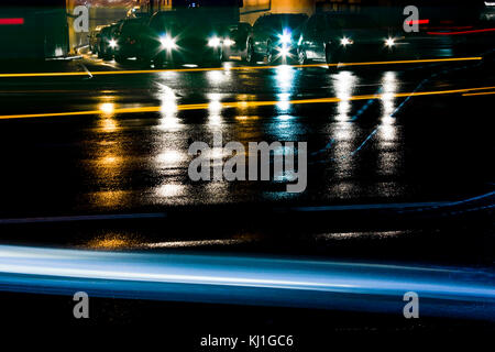 Nacht regen Verkehr auf den Straßen der Stadt. Autos im Tunnel die Ausfahrt an der Kreuzung warten in der Warteschlange beim Fahren Fahrzeuge bewegten Vergangenheit in motion blur lig verlassen Stockfoto