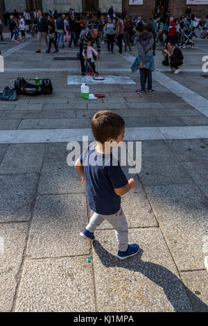 Ein kleiner Junge Genießen der Straßenkünstler. Piazza del Nettuno. Das Leben in der Stadt Bologna, Italien. Stockfoto