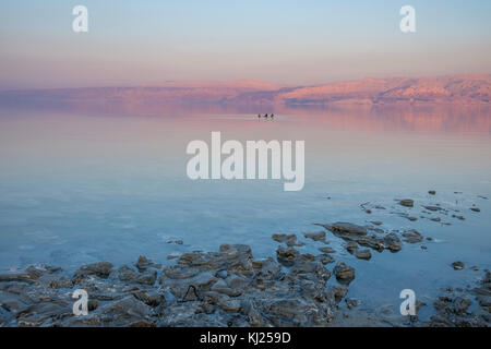 Liebhaber schwimmend auf dem Toten Meer bei Sonnenuntergang Zeit. Auf dem Hintergrund, den Jordan Berge verwandeln zu dieser Zeit des Tages rot. Stockfoto