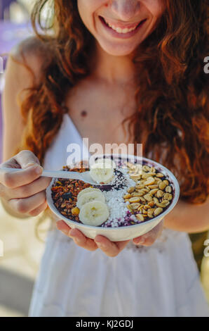 Junge Frau das Essen einer acai in der Schüssel, mit Banane, Mutter und Tapioka. Eine typische tropische Essen. Stockfoto