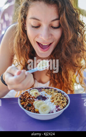 Junge Frau das Essen einer acai in der Schüssel, mit Banane, Mutter und Tapioka. Eine typische tropische Essen. Stockfoto